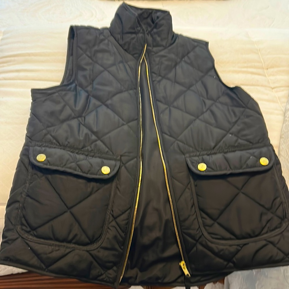 Black puffer vest with gold snap pockets and gold zipper